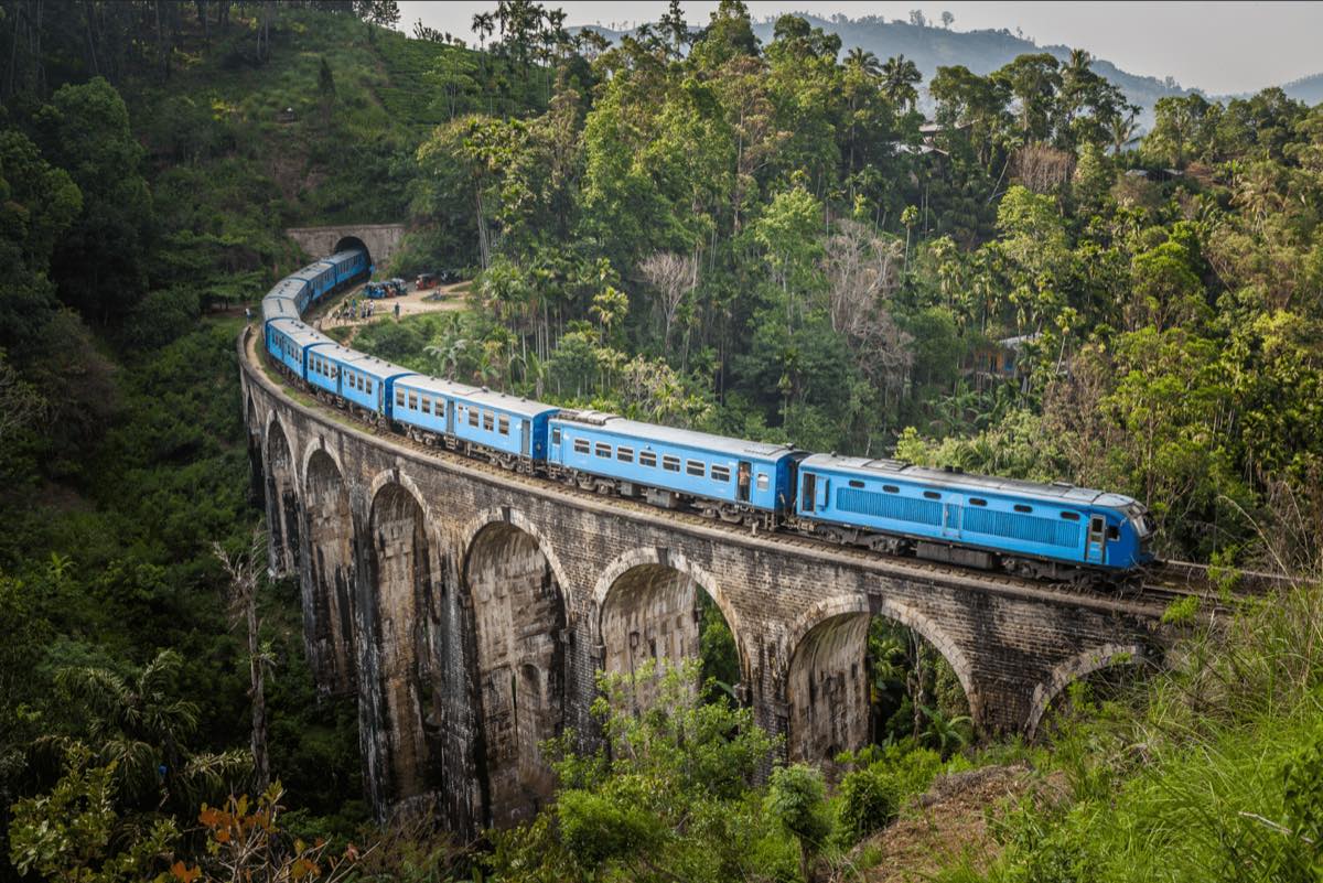 A blue train crossing the Nine Arches Bridge at Ella